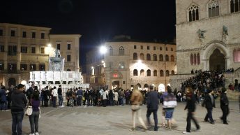 Scorso serale di Piazza IV novembre, a Perugia, con passanti e persone in fila fuori da Palazzo dei Priori